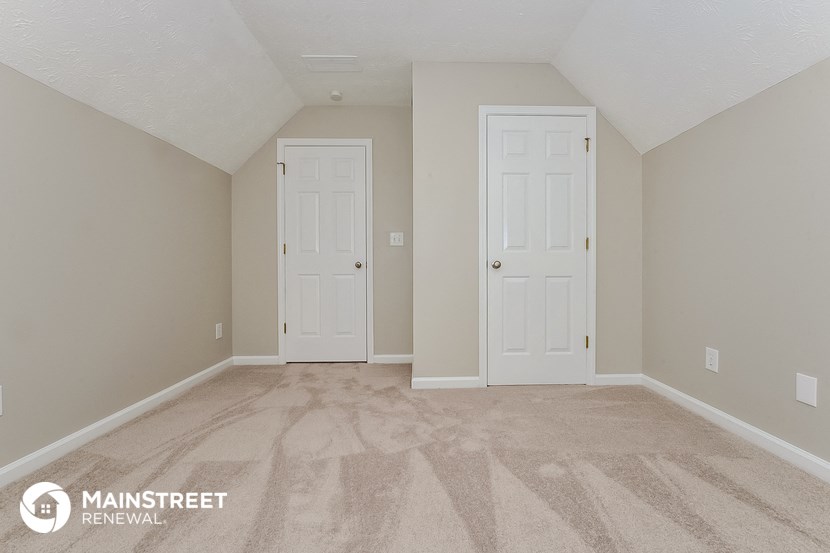 the upstairs bedroom with two doors and a carpeted floor