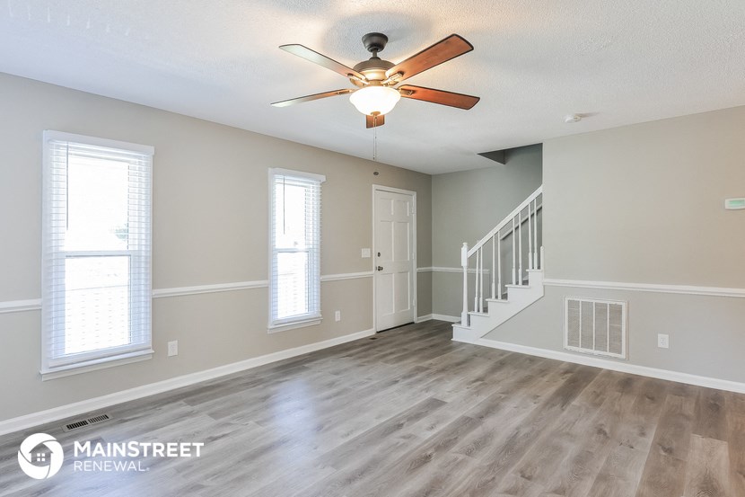 the spacious living room with stairs and a ceiling fan