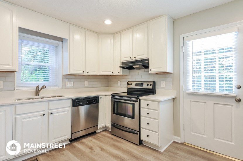 a white kitchen with stainless steel appliances and white cabinets