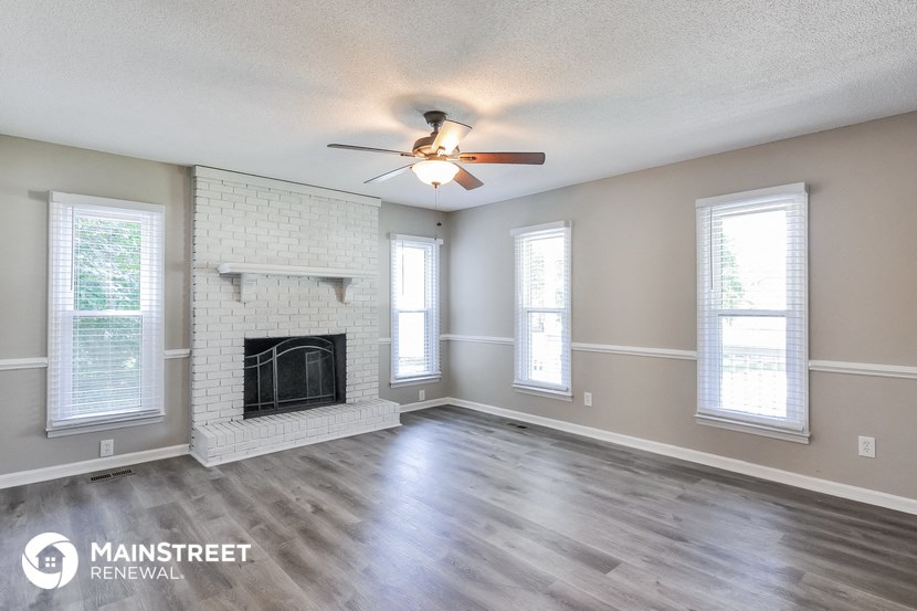 the living room with fireplace and ceiling fan