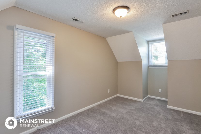 the spacious living room of this manufactured home has carpeting and a large window