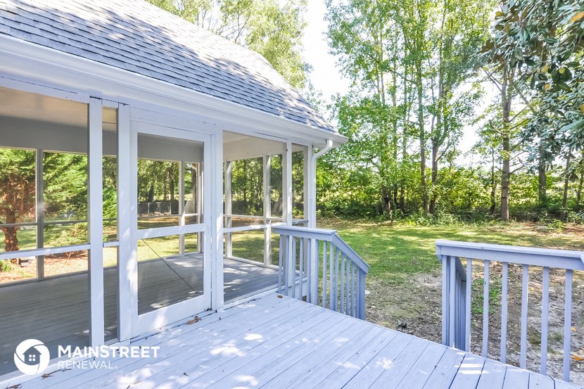 a covered porch with trees in the background