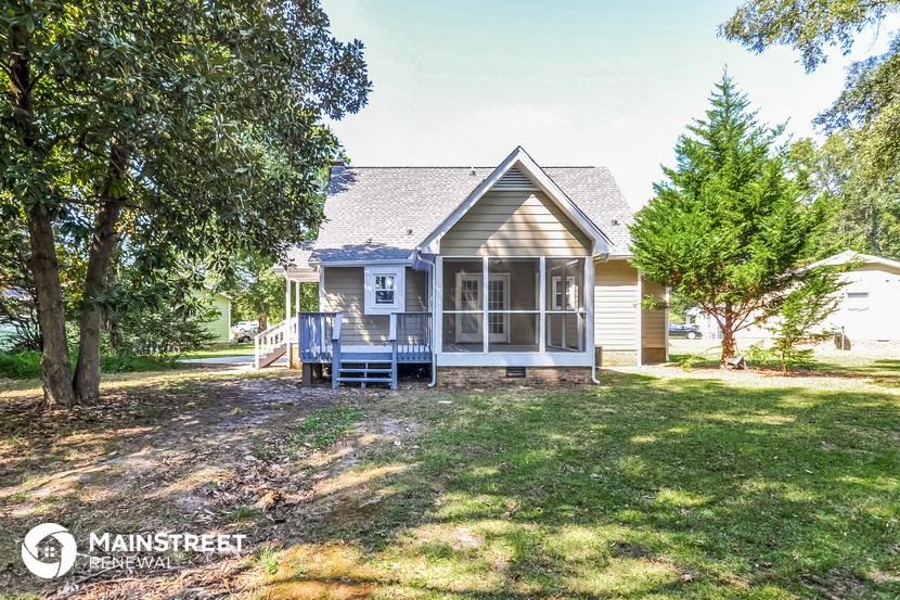 a small house with a yard and trees in front of it
