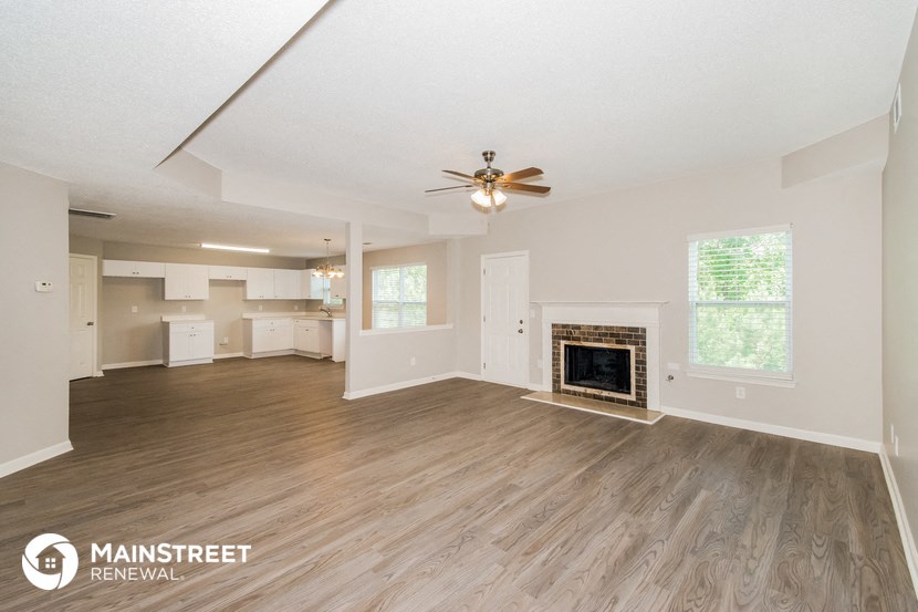 a living room with a fireplace and a ceiling fan