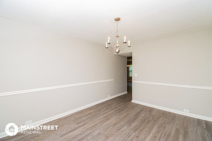 a spacious living room with white walls and wood flooring