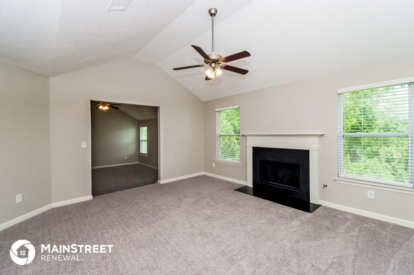 the living room with fireplace and ceiling fan