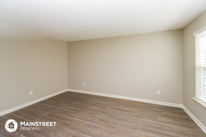 the spacious living room with wood flooring and white walls