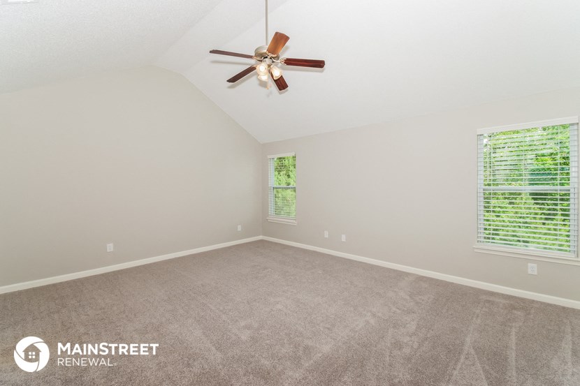 the spacious living room with carpeting and a ceiling fan