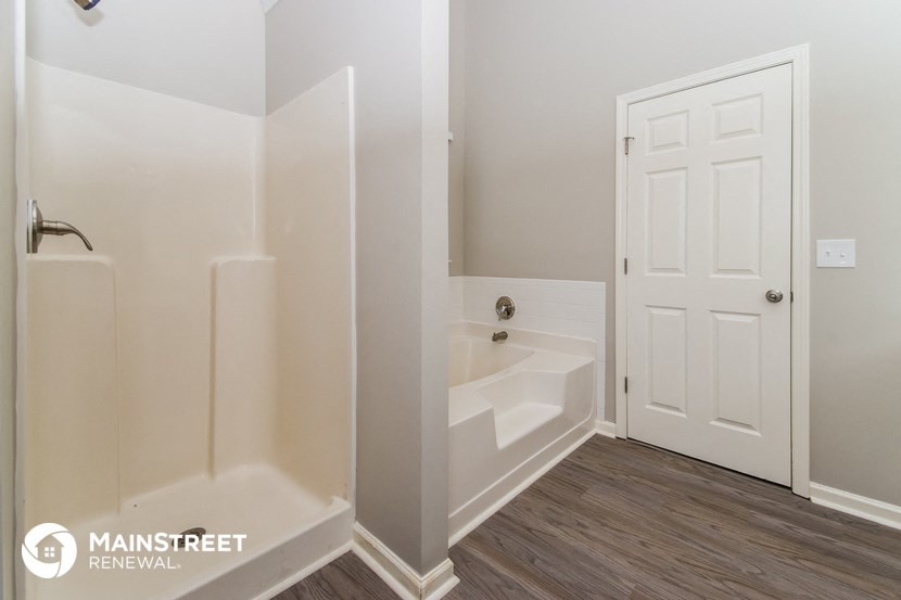a bathroom with a tub and a sink and a white door