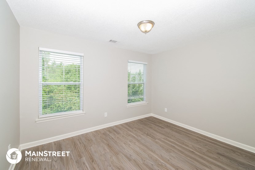 the spacious living room with wood flooring and two windows
