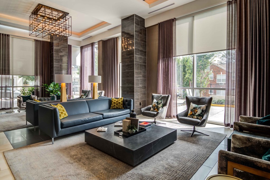 a living room with couches and chairs and large windows