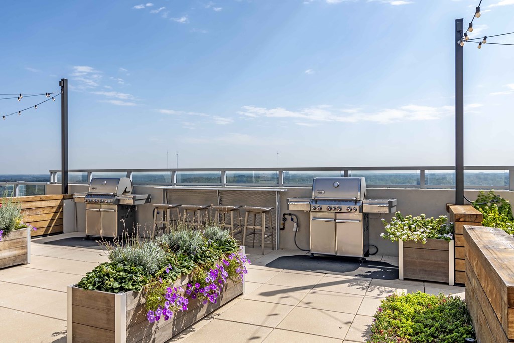 a rooftop patio with barbecue grills and plants