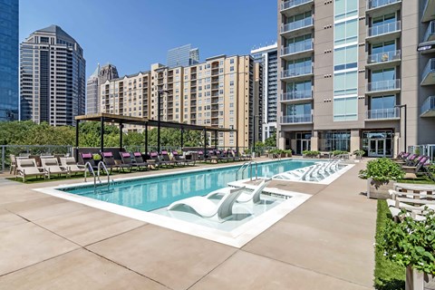 a swimming pool with lounge chairs in front of an apartment building