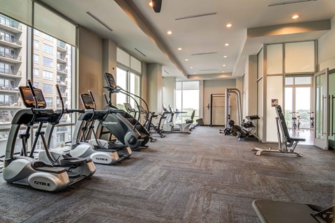a gym with cardio equipment on the floor and large windows