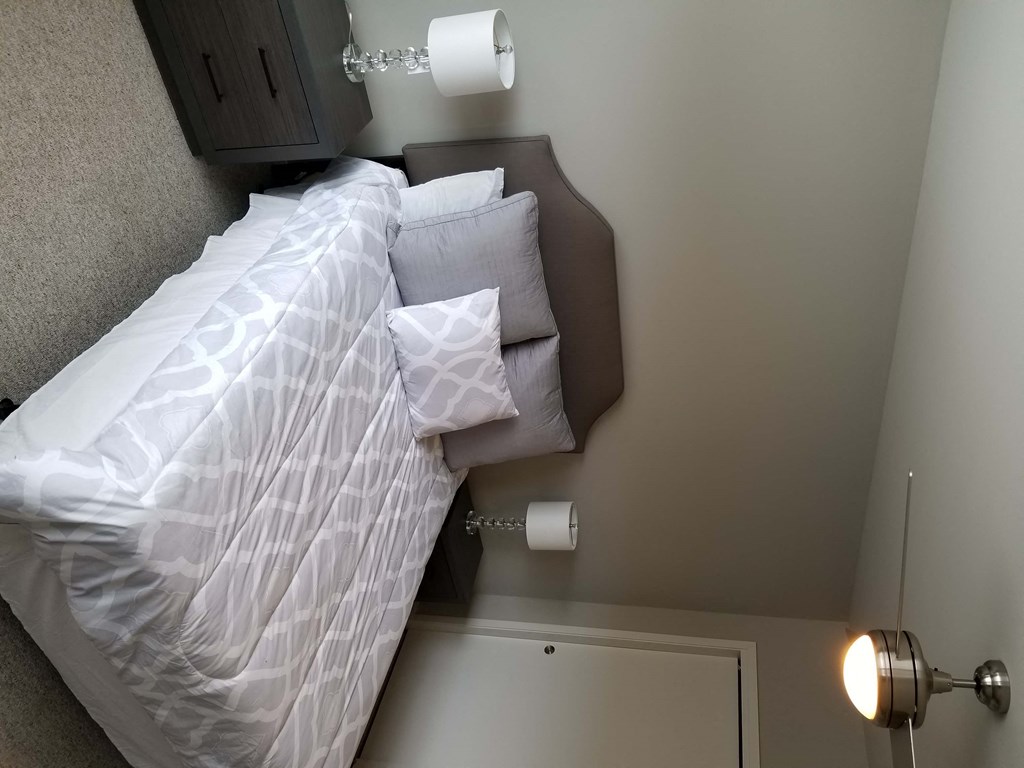a bed in a small room with a white comforter and pillows