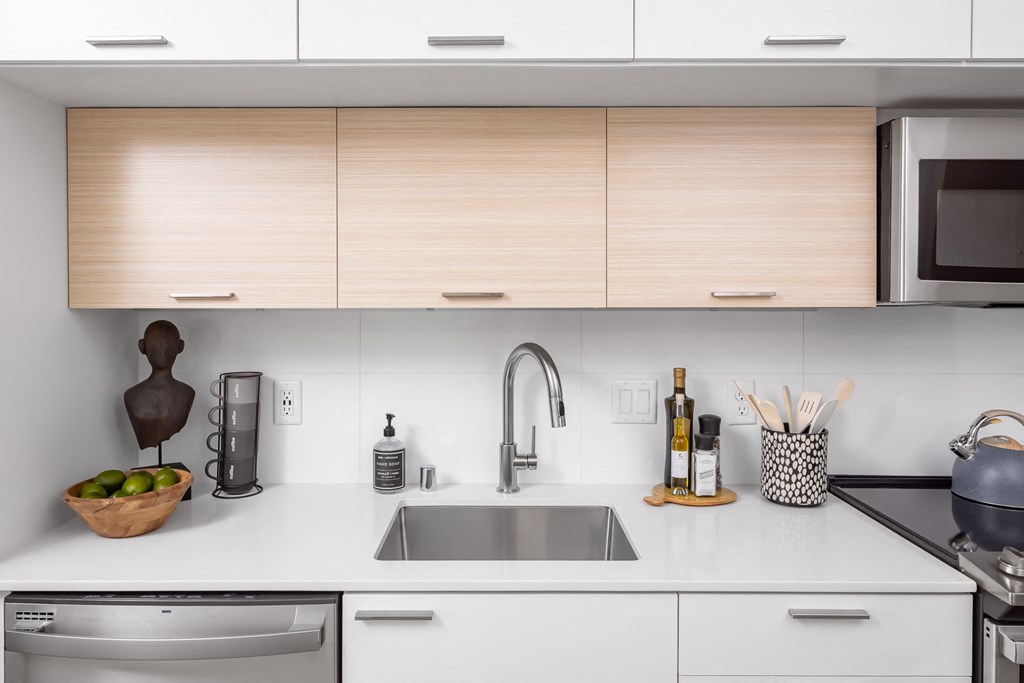 Kitchen with stainless steel appliances, white granite countertops and light colored wood cabinets at Platform