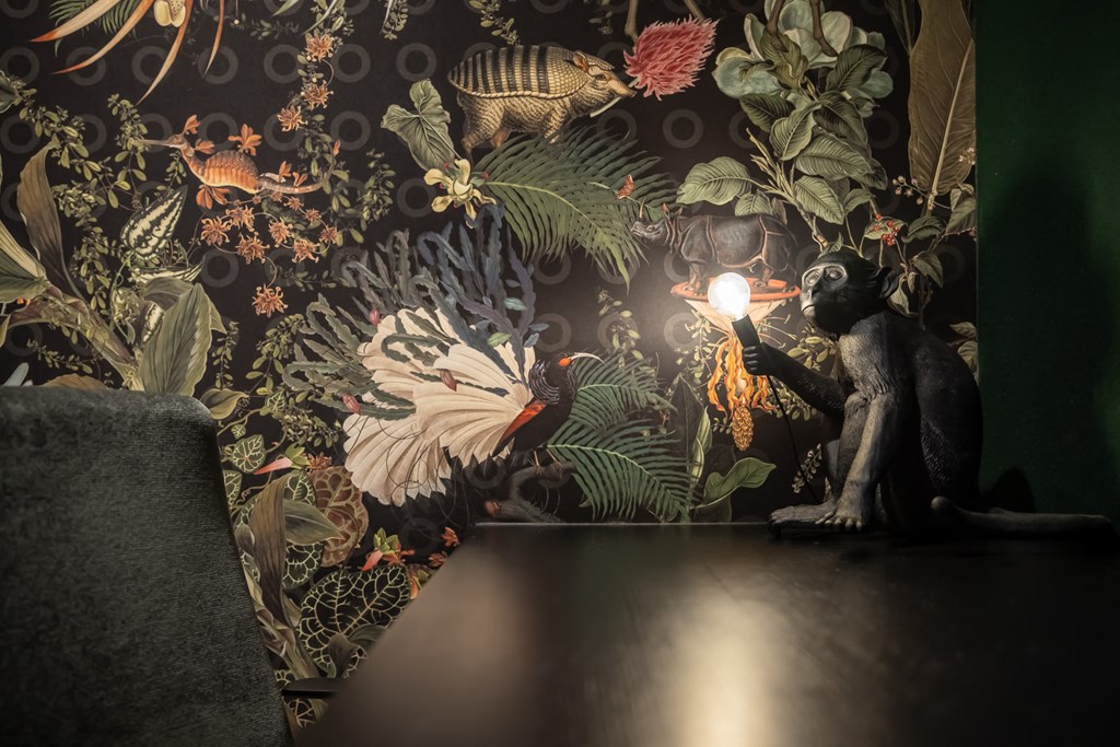 Private office with dark floral wallpaper and black monkey accent lamp