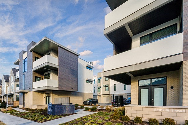 a row of modern houses with balconies and a sidewalk