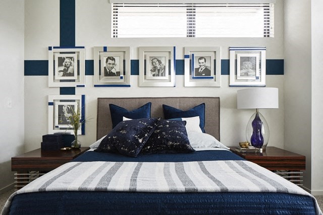 a blue and white bedroom with a bed and pictures on the wall