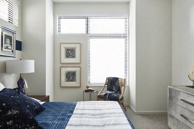 a bedroom with a bed and a chair and a window