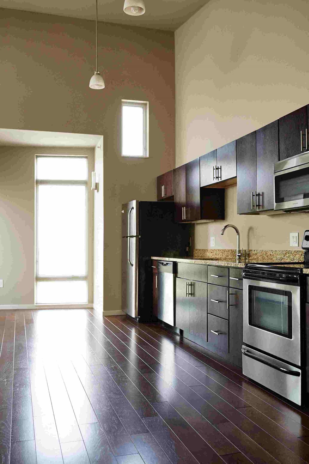 an empty kitchen with stainless steel appliances and wooden floors