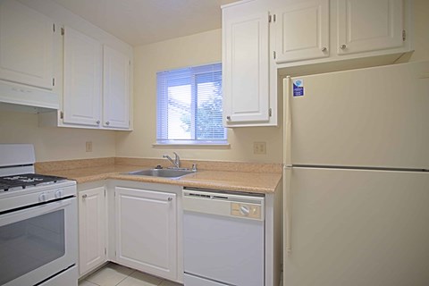 A kitchen with white cabinets and appliances.