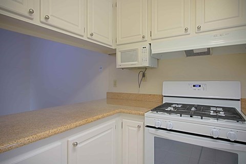 A kitchen with a white oven and cabinets.