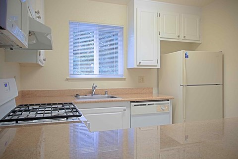 A kitchen with a white refrigerator, sink, and stove.