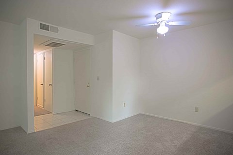 A room with a ceiling fan and carpeted floor.