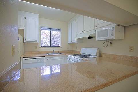 A kitchen with white cabinets and a granite countertop.