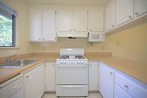 A white stove in a kitchen with white cabinets.