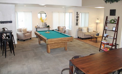 A pool table is surrounded by chairs in a room.