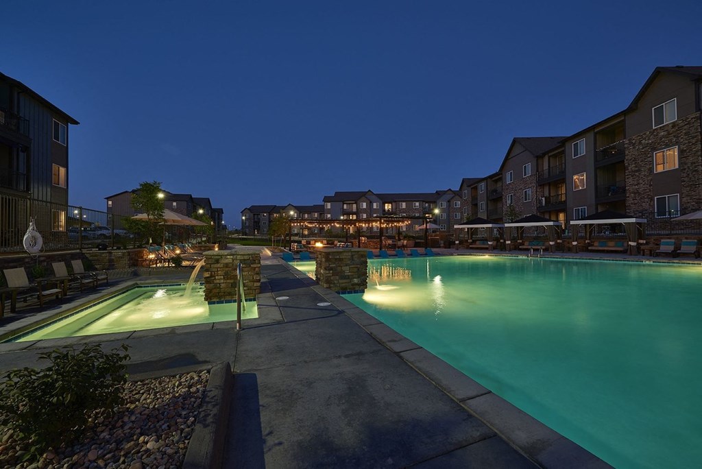 a swimming pool at night at an apartment complex
