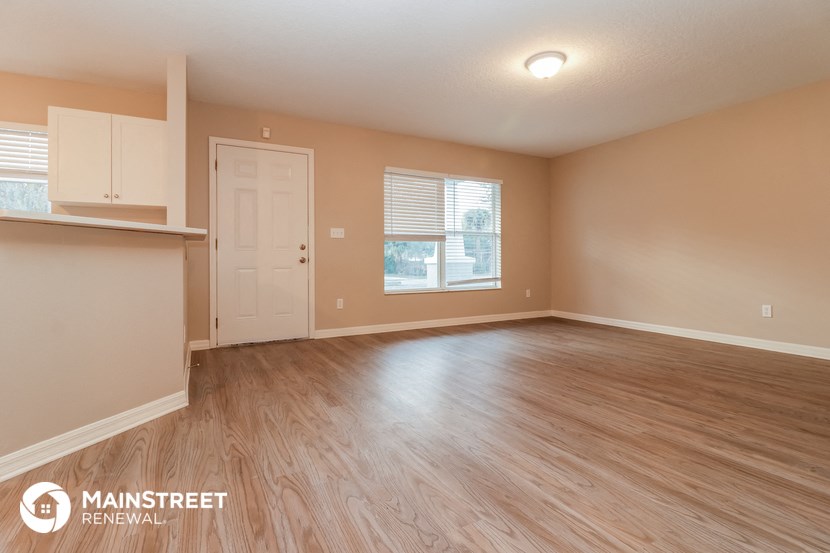 an empty living room with wood flooring and a white door