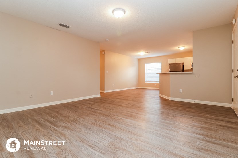the living room and kitchen of a renovated house with wood flooring