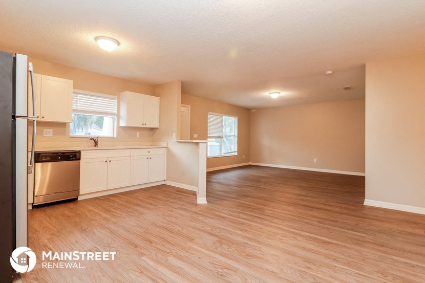 an empty kitchen and living room with a wooden floor