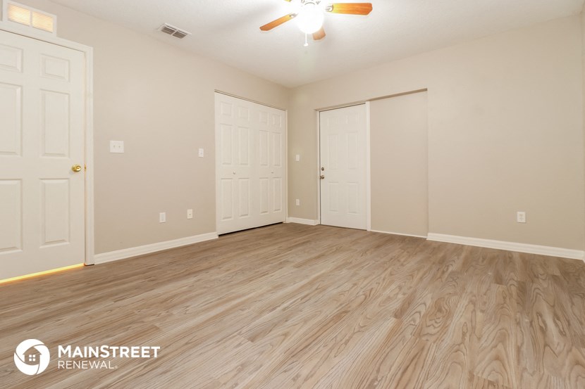 the living room of a home with wood flooring and a ceiling fan