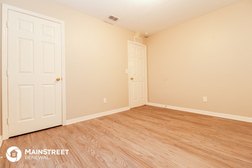 the living room of a home with wood flooring and two doors