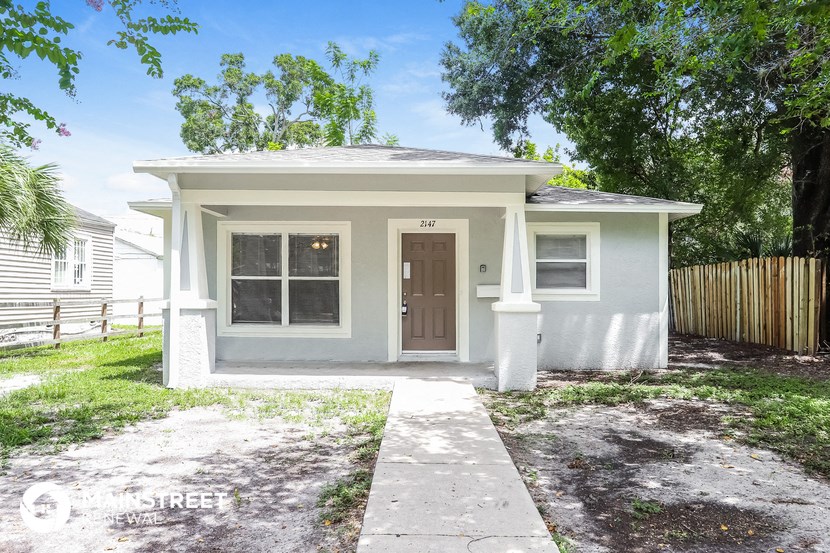 a small white house with a sidewalk and a door