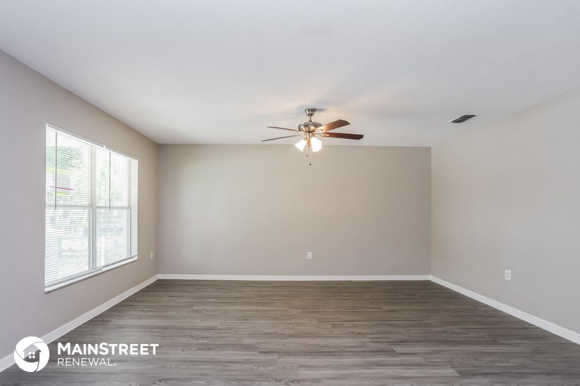 an empty living room with a ceiling fan and a window