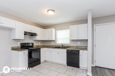 a kitchen with white cabinets and black appliances