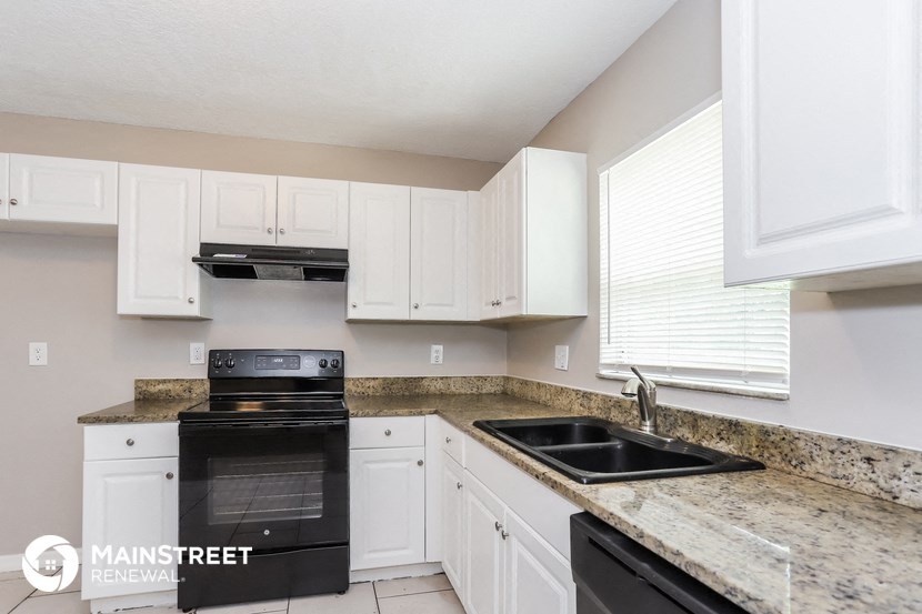 a kitchen with white cabinets and black appliances