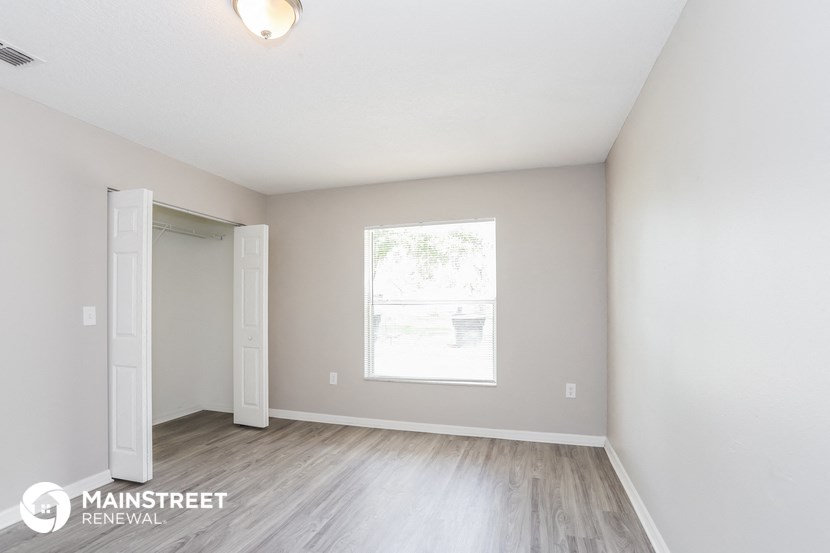 the living room with wood flooring and a large window