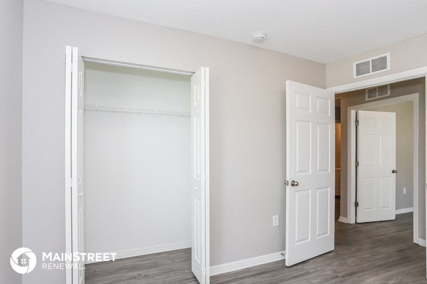 the living room of an apartment with white doors and a hallway to the bedroom