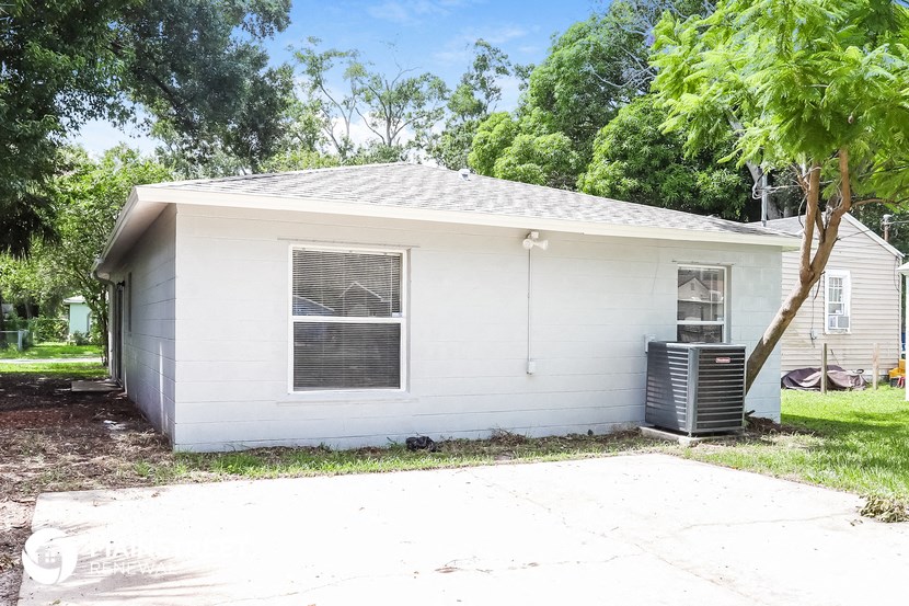 a small white house with a garage and a tree