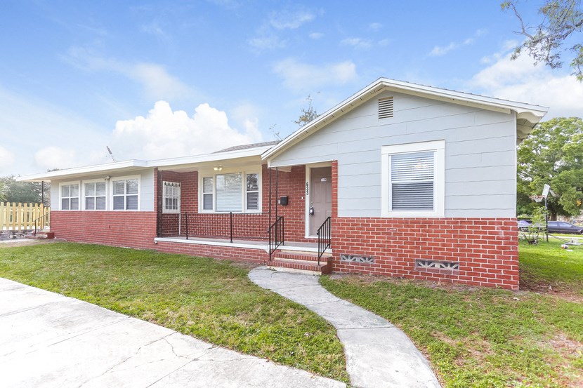 a small brick house with a sidewalk in front of it