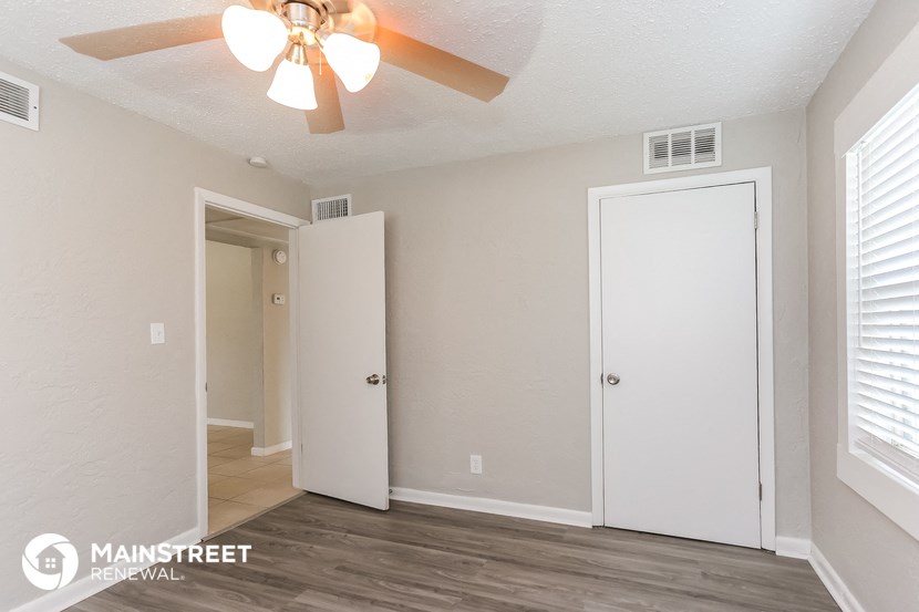 a bedroom with a ceiling fan and a door to a closet