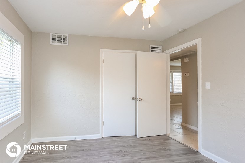 the living room of an apartment with white walls and a ceiling fan