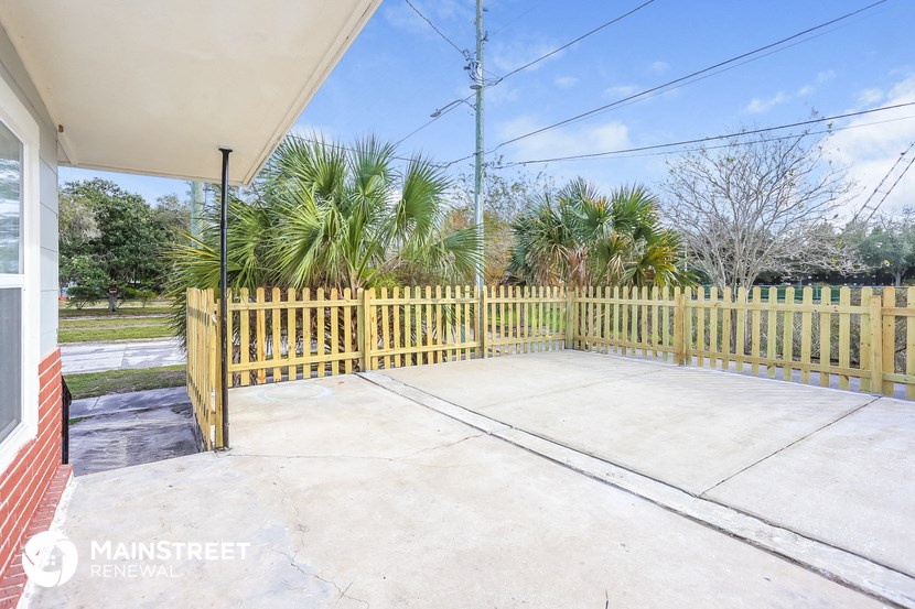 a patio with a yellow fence and a white house