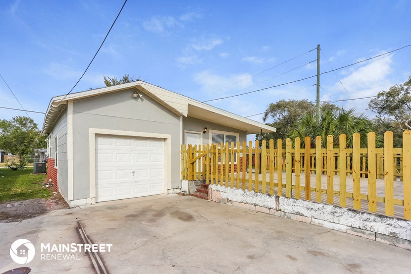 a small house with a yellow fence and a white garage door